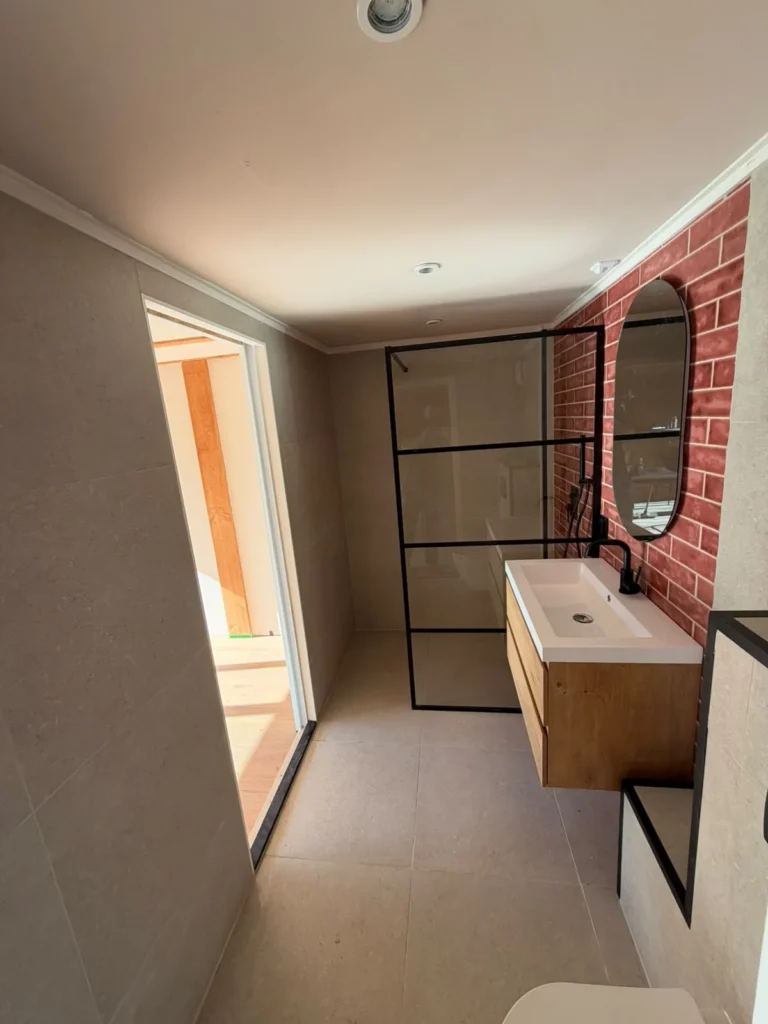 Gerenoveerde badkamer met inloopdouche, zwevend badmeubel en wand met rode steenstrips in Apeldoorn