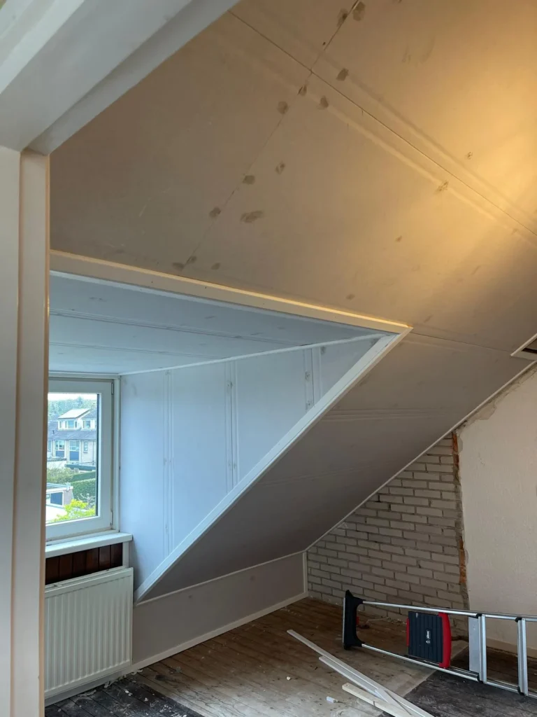 Binnenzijde van een dakkapel op zolder, afgetimmerd met witte panelen in Apeldoorn