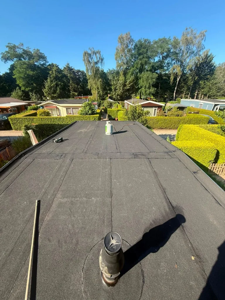 Plat dak met nieuwe bitumen dakbedekking en ontluchting op een chalet in Apeldoorn