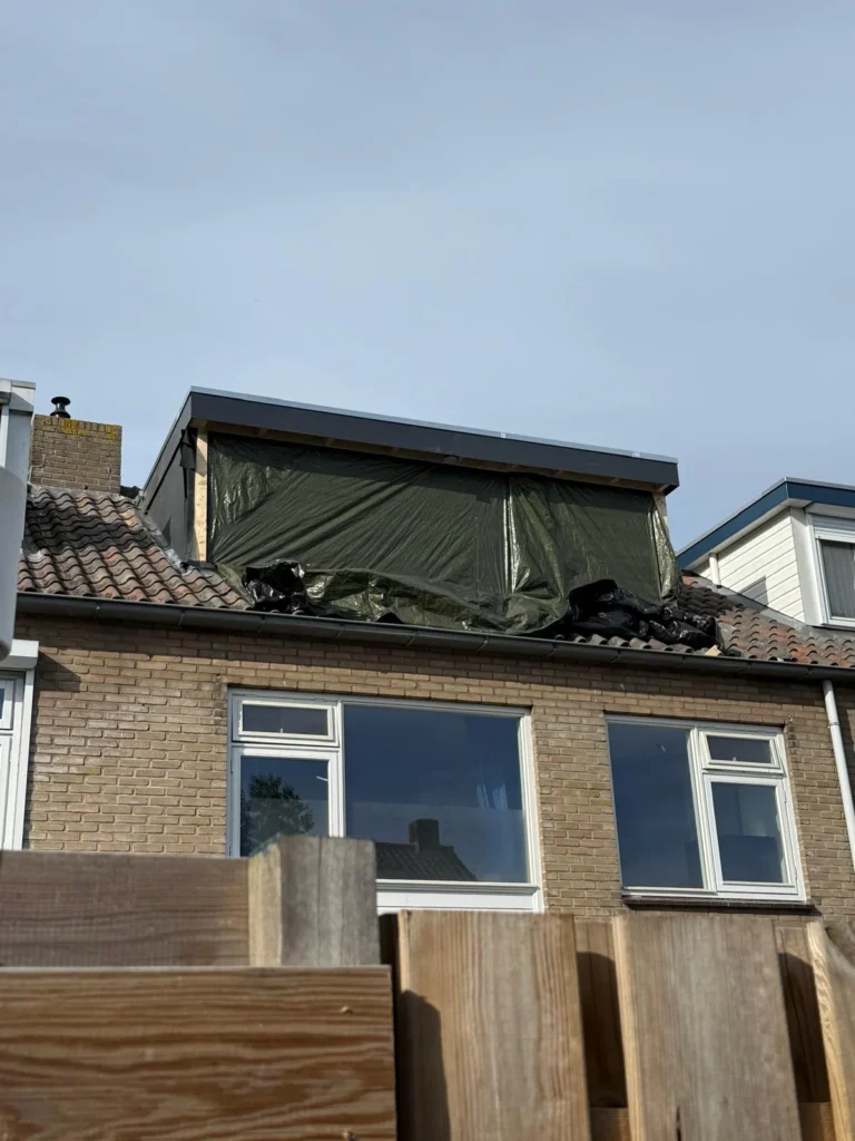 Nieuwe dakkapel in aanbouw, afgedekt met folie, op een pannendak in Teuge