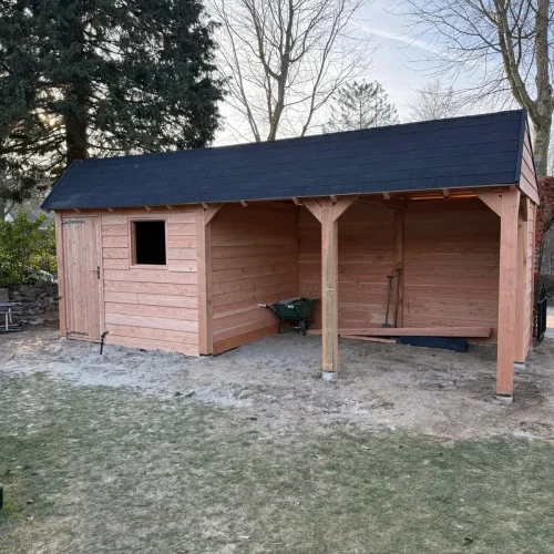 Douglas houten tuinhuis met overkapping en zwarte dakshingles in een tuin in Apeldoorn
