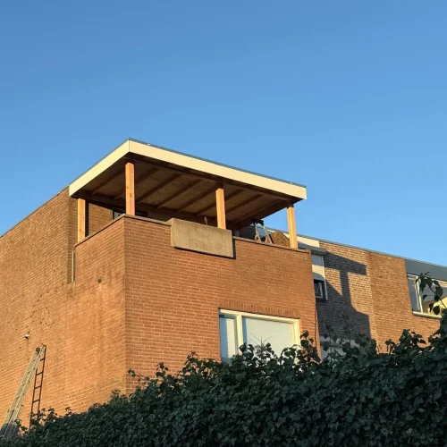 Houten overkapping met wit dakrandprofiel op een dakterras van een bakstenen woning in Apeldoorn