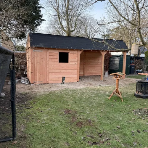 Houten tuinhuis met overkapping en zwart dak achter in een tuin in Apeldoorn